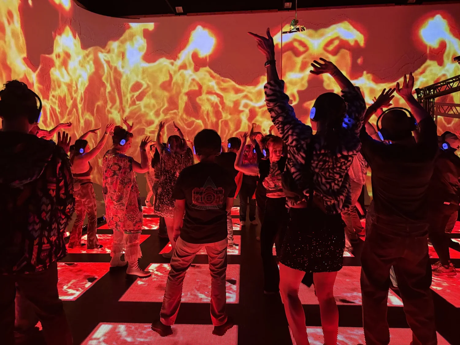 Crowd dancing on LED floor with fire projections