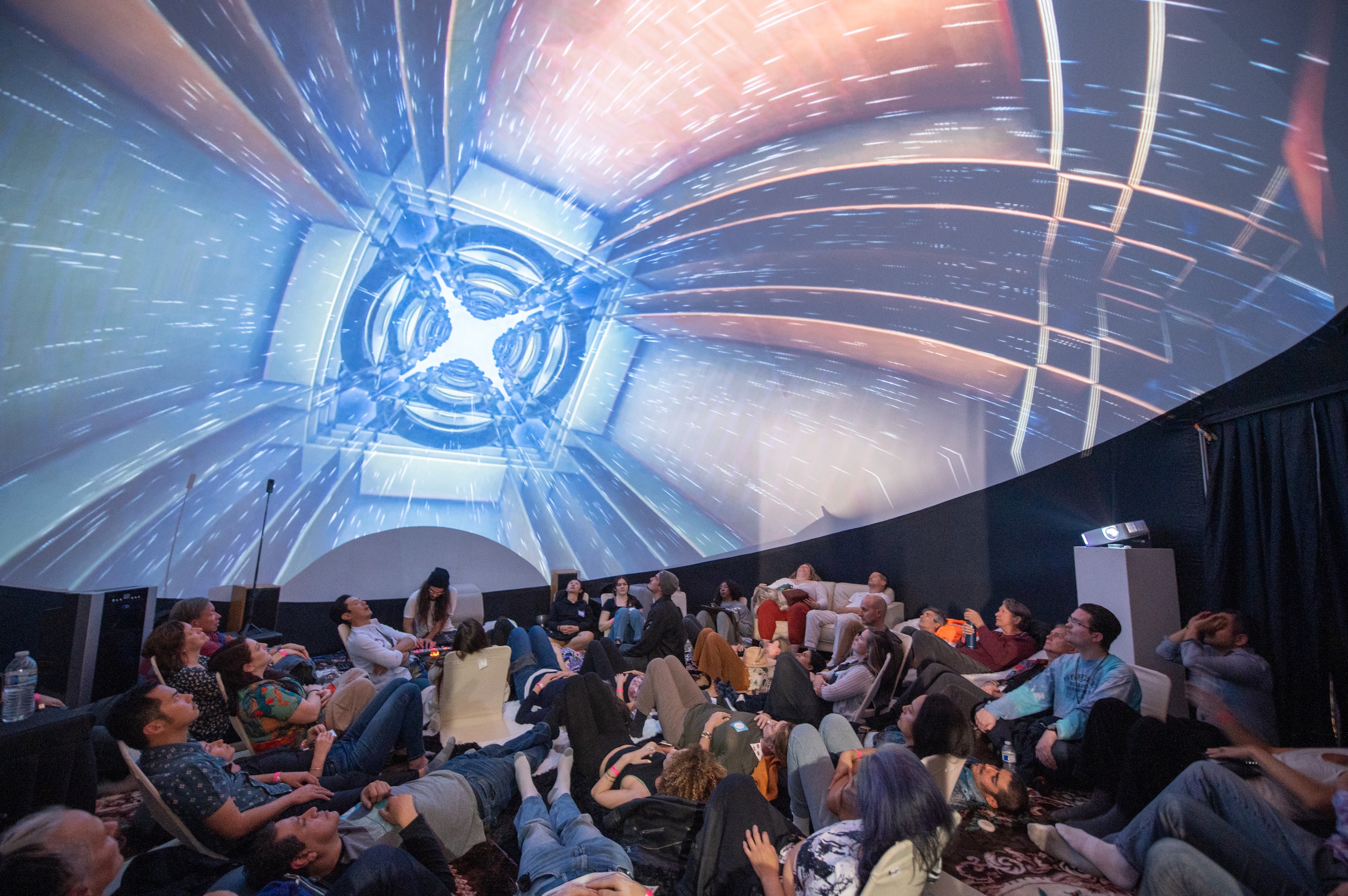 Audience immersed in blue geometric portal projections inside the dome