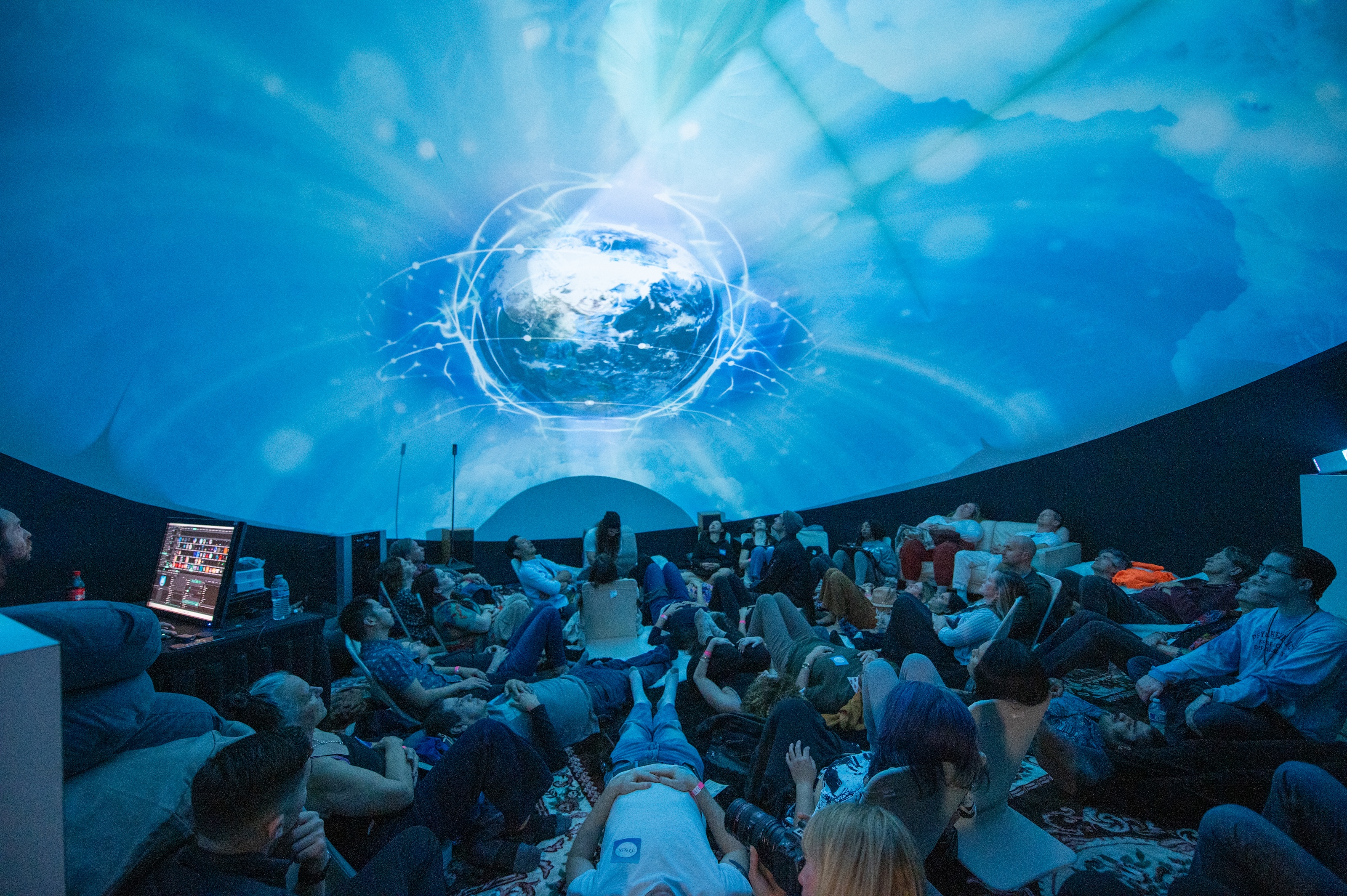 Earth hologram projection with audience gazing upward inside the dome