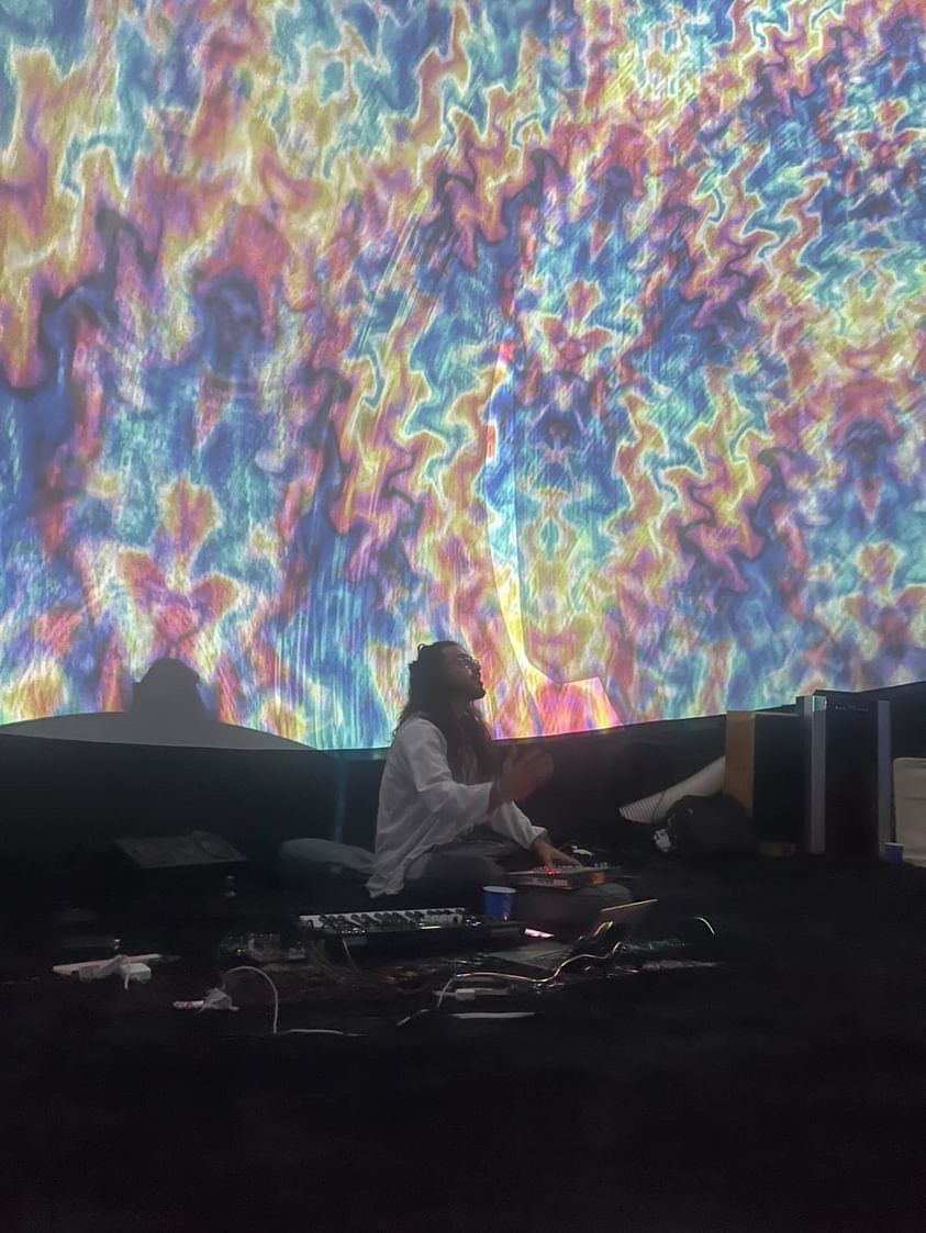 Performer surrounded by psychedelic color projections inside the dome